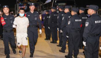 Chinese police officers escort gambling and scam suspects at Phnom Penh International Airport in Cambodia (Xinhua/Shutterstock)

