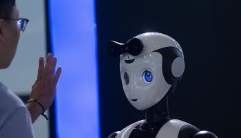 A visitor is interacting with a humanoid robot at the World Artificial Intelligence Conference in Shanghai (Ying Tang/NurPhoto/Shutterstock)