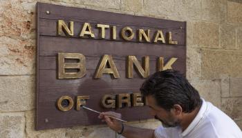 A man painting a sign of the National Bank of Greece (imageBROKER/Shutterstock)

