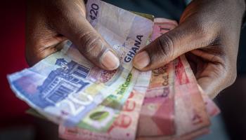 A man holds a bundle of Ghanaian banknotes (Cristina Aldehuela/Bloomberg/Getty Images)