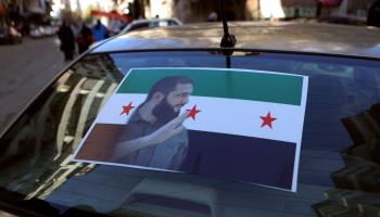 Image of HTS commander Ahmed al-Sharaa and new Syrian flag (Aaref Watad/AFP/Getty Images)