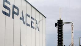 A SpaceX building at the Kennedy Space Center with a Falcon 9 rocket in the background, Florida, September 9, 2025 (Joe Raedle/Getty Images)